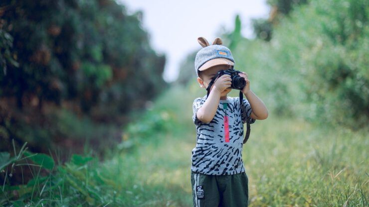 Chłopiec w shortach robi zdjęcia aparatem fotograficznym